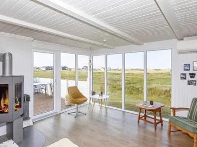 a living room with a fireplace and views of a field at 6 person holiday home in Thisted in Torsted
