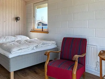 a bedroom with a bed and a chair and a window at 6 person holiday home in Thisted in Torsted
