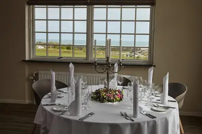 a table with a white table cloth and flowers on it at Hotel Nor - Badehotellet in Fjerritslev