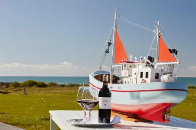 a bottle of wine and a glass on a table with a boat at Hotel Nor - Badehotellet in Fjerritslev