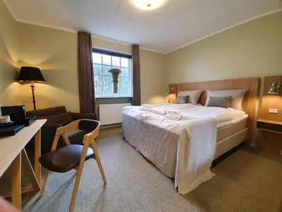 a bedroom with a bed and a desk and a chair at Hotel Nor - Badehotellet in Fjerritslev