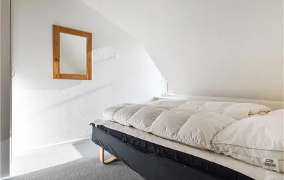 a bed in a white room with a mirror on the wall at Lovely Apartment In Lemvig With Kitchen in Lemvig