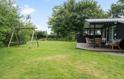 a house with a porch with a swing and a yard at Cozy Home In Hjerm With Kitchen in Hjerm