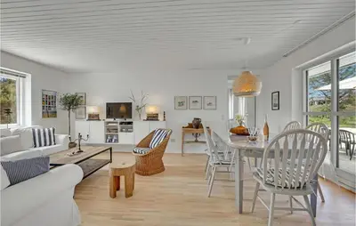 a dining room and living room with a table and chairs at 4 Bedroom Gorgeous Home In Blokhus in Blokhus