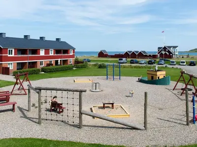a playground with swings and play equipment in a yard at 5 person holiday home on a holiday park in Lemvig in Lemvig