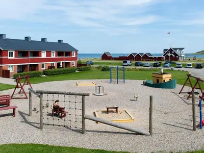a playground with swings and play equipment in a yard at 5 person holiday home on a holiday park in Lemvig in Lemvig