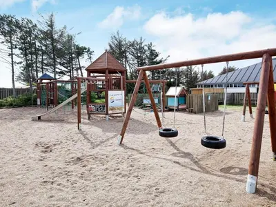 a playground with a swing set in the sand at 6 person holiday home on a holiday park in Blokhus in Blokhus