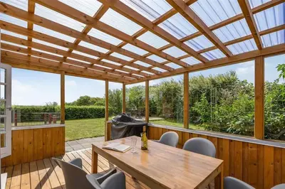 a patio with a wooden pergola and a wooden table and chairs at Thatched Holiday Home in Struer, Jutland with a view in Struer