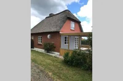 a small red house with a thatched roof at Thatched Holiday Home in Struer, Jutland with a view in Struer