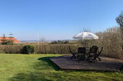 two chairs and an umbrella on a wooden deck at Thatched Holiday Home in Struer, Jutland with a view in Struer