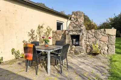 a table and chairs with a stone fireplace in a yard at Logi i hus med kunst og have in Vestervig