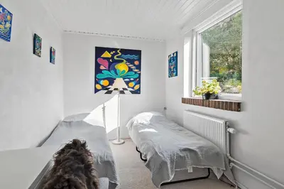 a bedroom with a bed and a window at Logi i hus med kunst og have in Vestervig