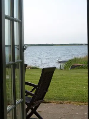 a bench sitting in front of a window looking at the water at Skibstedgaard in Hurup
