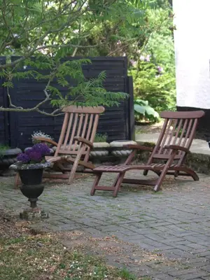 two wooden chairs sitting on a patio with flowers at Skibstedgaard in Hurup