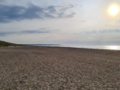 a sandy beach with the sun in the sky at 6 person holiday home in Brovst in Brovst