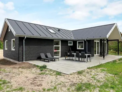 a black house with a patio with chairs and tables at 10 person holiday home in Thisted in Thisted