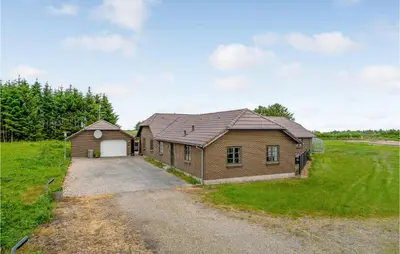 a brown house with a garage in a field at Gorgeous Home In Hanstholm With Kitchen in Hanstholm