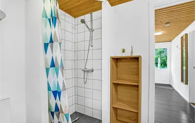 a bathroom with a shower with a blue and white shower curtain at Cozy Home In Øster Assels With Sauna in Øster Assels
