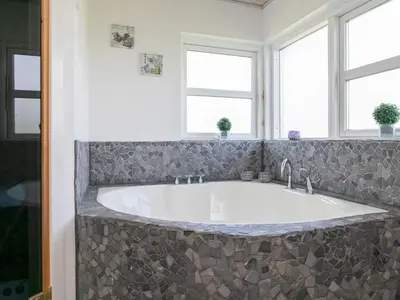 a large tub in a bathroom with two windows at 6 person holiday home in Brovst in Brovst