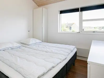 a white bedroom with a large bed with a window at 6 person holiday home in Brovst in Brovst