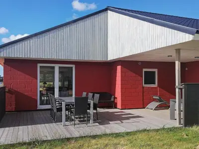a red house with a table and chairs on a deck at Luxury Dunes Retreat-By Traum in Pandrup