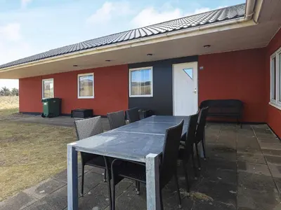 a table and chairs on a patio with a house at Luxury Dunes Retreat-By Traum in Pandrup