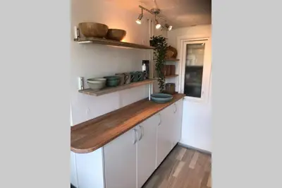 a kitchen with white cabinets and a wooden counter top at Seaside VØ in Nørre Vorupør