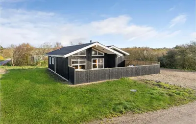 a black house with a black roof on a grass field at Awesome Home In Vestervig With Sauna in Vestervig