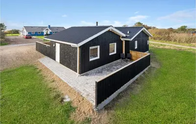 a black house with a fence in a yard at Awesome Home In Vestervig With Sauna in Vestervig
