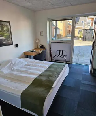 a bedroom with a bed and a desk and a window at Hotel Phønix in Holstebro