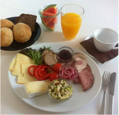 a plate of food with cheese and vegetables on a table at Hotel Phønix in Holstebro