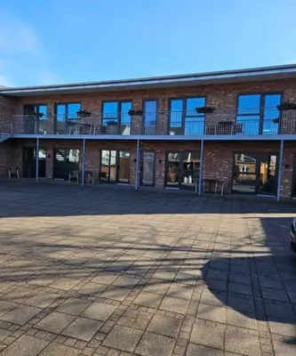 a brick building with a parking lot in front of it at Hotel Phønix in Holstebro