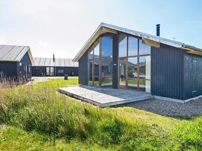 a wooden house with glass windows on a field at Tranquil Retreat in Thorsminde-By Traum in Ulfborg