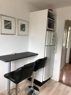 a kitchen with a table and two chairs and a refrigerator at BrusaaUdlejning in Nibe