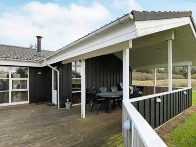 a covered deck with a table and chairs at Luxury Retreat in Gronhoj-By Traum in Løkken