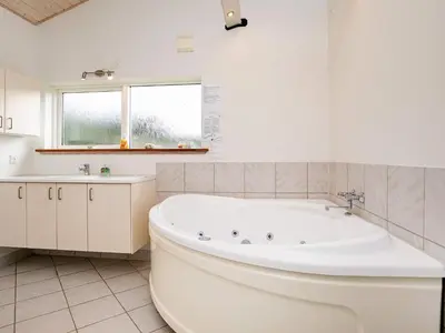 a white bathroom with a tub and a sink at Luxury Retreat in Gronhoj-By Traum in Løkken