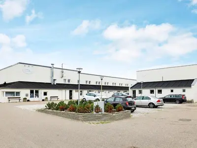 a large building with cars parked in a parking lot at Cozy Cottage in Skaven Strand-By Traum in Brovst