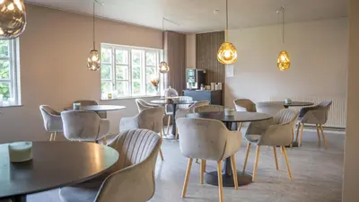 a dining room with tables and chairs and lights at Hotelcity in Holstebro