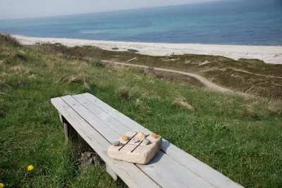 a wooden bench sitting on top of a beach at Sommerhus Farmen i Hanstholm in Hanstholm