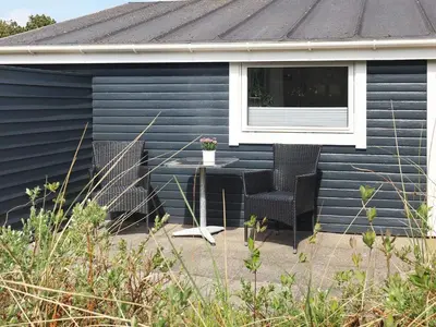 a blue house with a table and chairs and a window at Bright Coastal Retreat in Vorupor-By Traum in Thisted