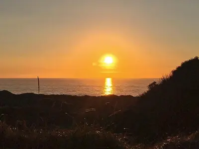 a sunset over the ocean with the sun setting at 6 person holiday home in Løkken in Løkken