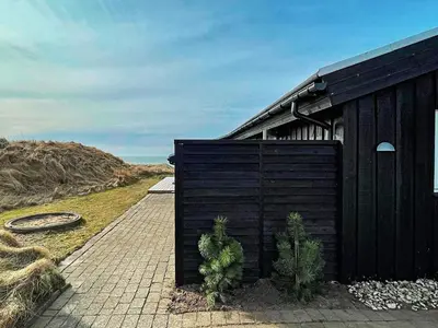 a black building with plants in front of it at 6 person holiday home in Løkken in Løkken