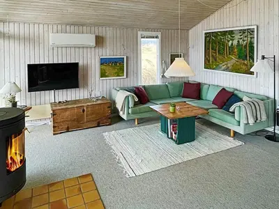 a living room with a green couch and a fireplace at 6 person holiday home in Løkken in Løkken