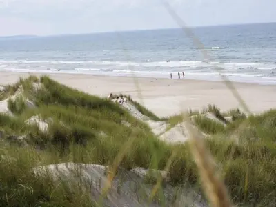 a beach with people on the sand and the ocean at 8 person holiday home in Blokhus in Blokhus