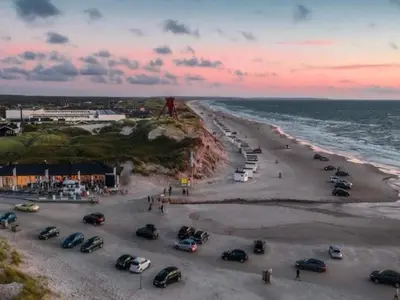 a group of cars parked on the beach at sunset at 8 person holiday home in Blokhus in Blokhus