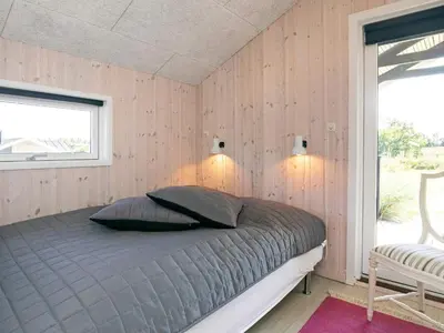 a bedroom with a bed in a room with wooden walls at 8 person holiday home in Blokhus in Blokhus