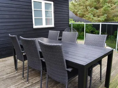 a wooden table and chairs on a deck at Tranquil Retreat in Blokhus-By Traum in Blokhus