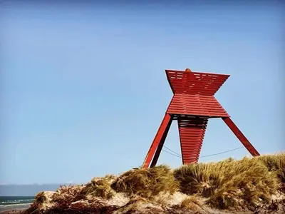 a red wooden structure on a sandy beach at Tranquil Retreat in Blokhus-By Traum in Blokhus