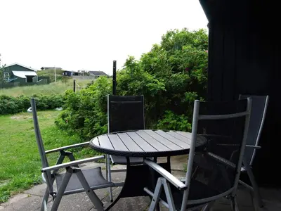 a wooden table and two chairs sitting next to a table at Tranquil Retreat in Blokhus-By Traum in Blokhus