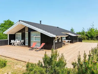 a house with a deck and chairs on it at 6 person holiday home in Løkken in Løkken